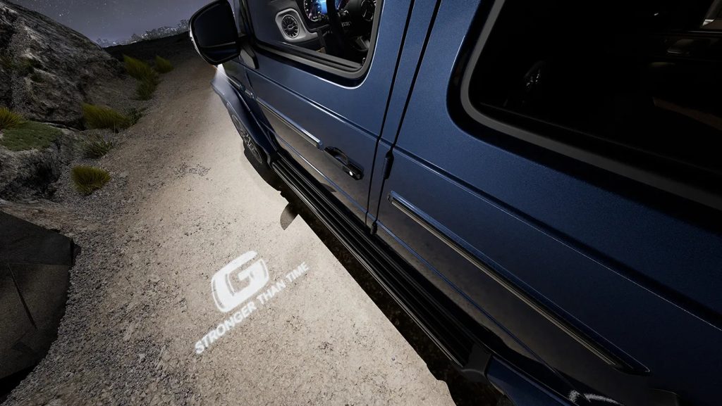 Close-up of G-Wagen door with “Stronger Than Time” logo projection, hinting at the design cues a Mini G-Wagen could inherit.