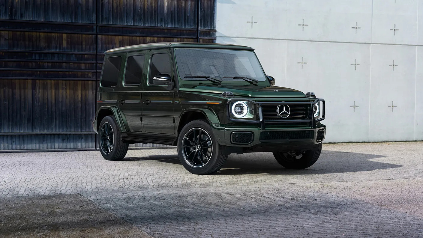 Front view of a green Mercedes-Benz G-Class SUV parked outside a modern building at Loeber Motors dealership.