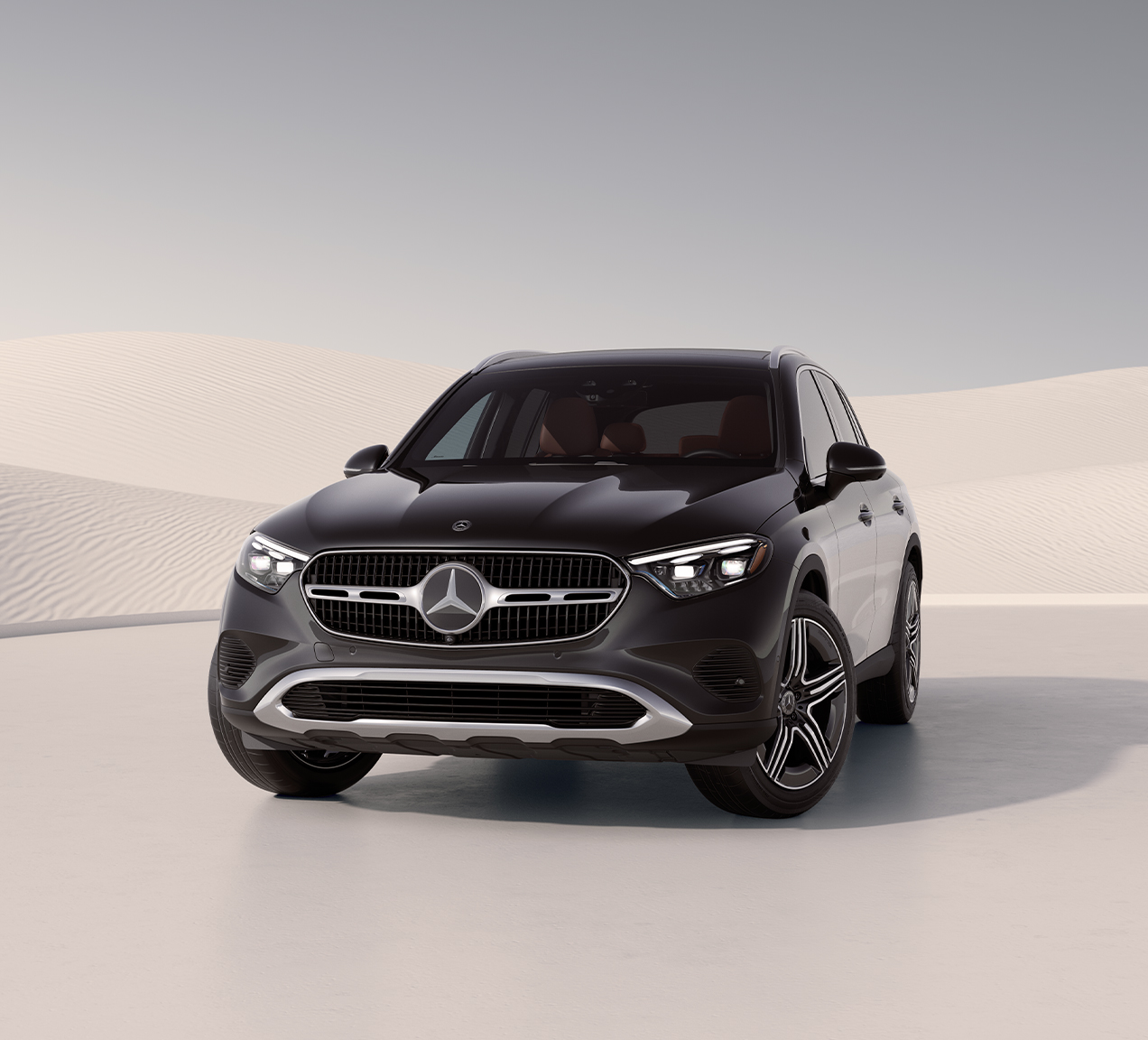 Front view of a black 2026 Mercedes-Benz GLC parked against a modern desert-inspired background.
