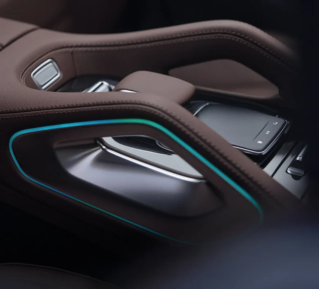 Close-up of the 2026 Mercedes-Benz GLE center console featuring brown leather, metallic trim, and ambient lighting that creates a cozy, premium cabin atmosphere.