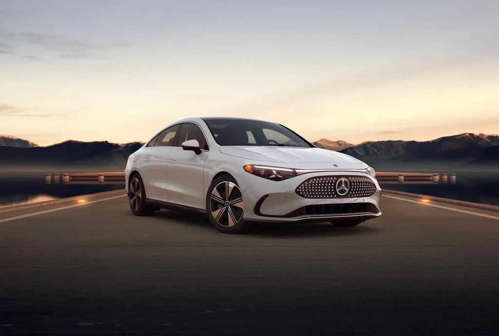 White new Mercedes-Benz CLA Electric parked on a roadway at sunset with mountains in the background, highlighting the model coming soon.
