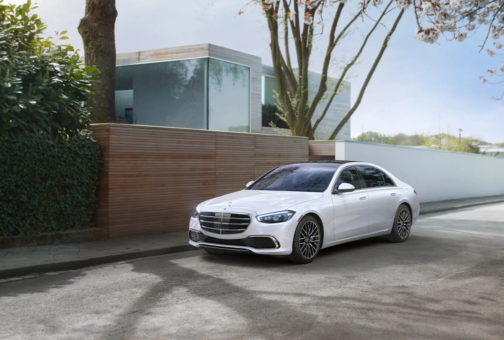 2027 Mercedes-Benz S-Class white luxury sedan parked near a modern home with sleek exterior styling.
