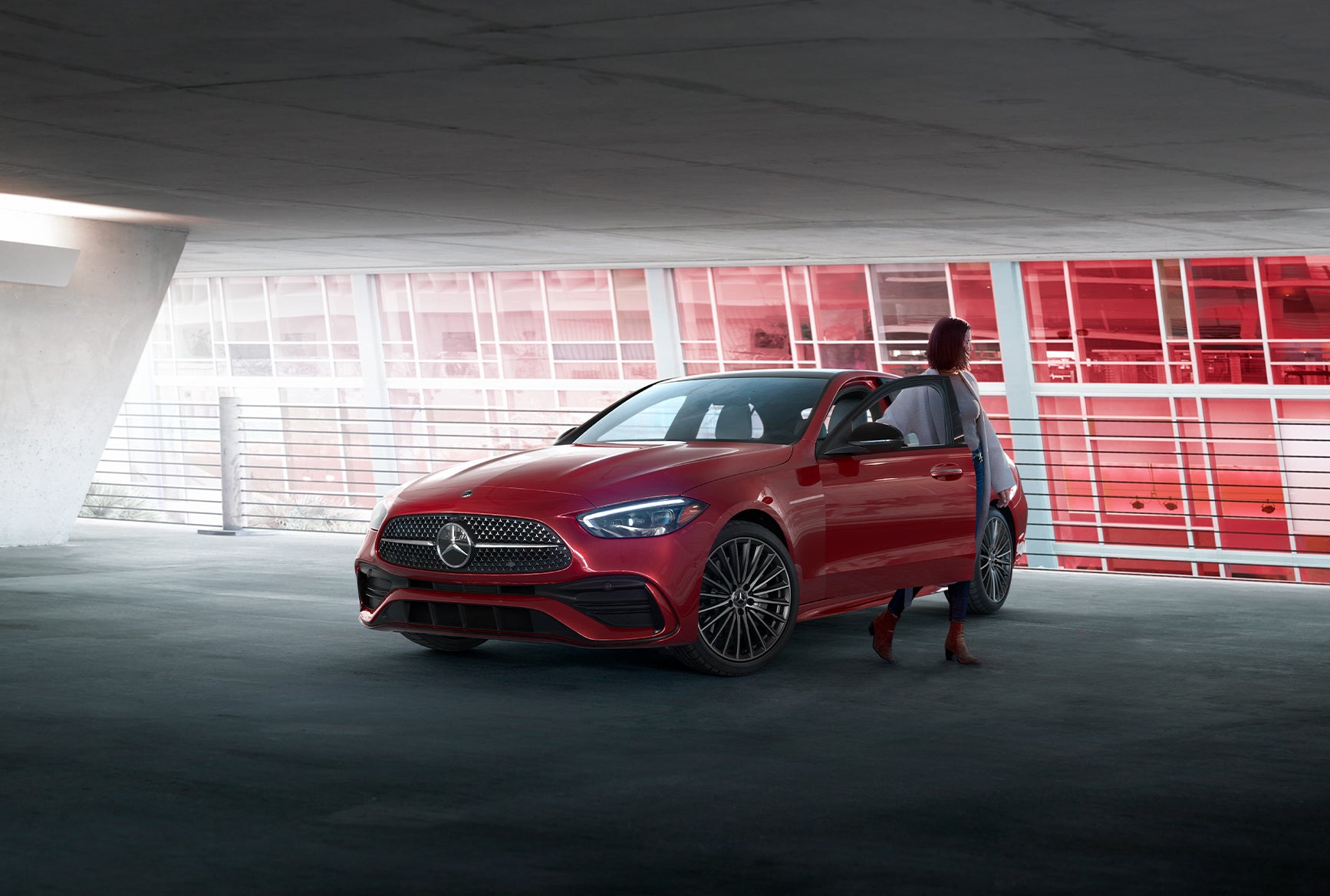 2027 Mercedes-Benz C-Class Sedan in red parked in a modern garage with the driver door open.