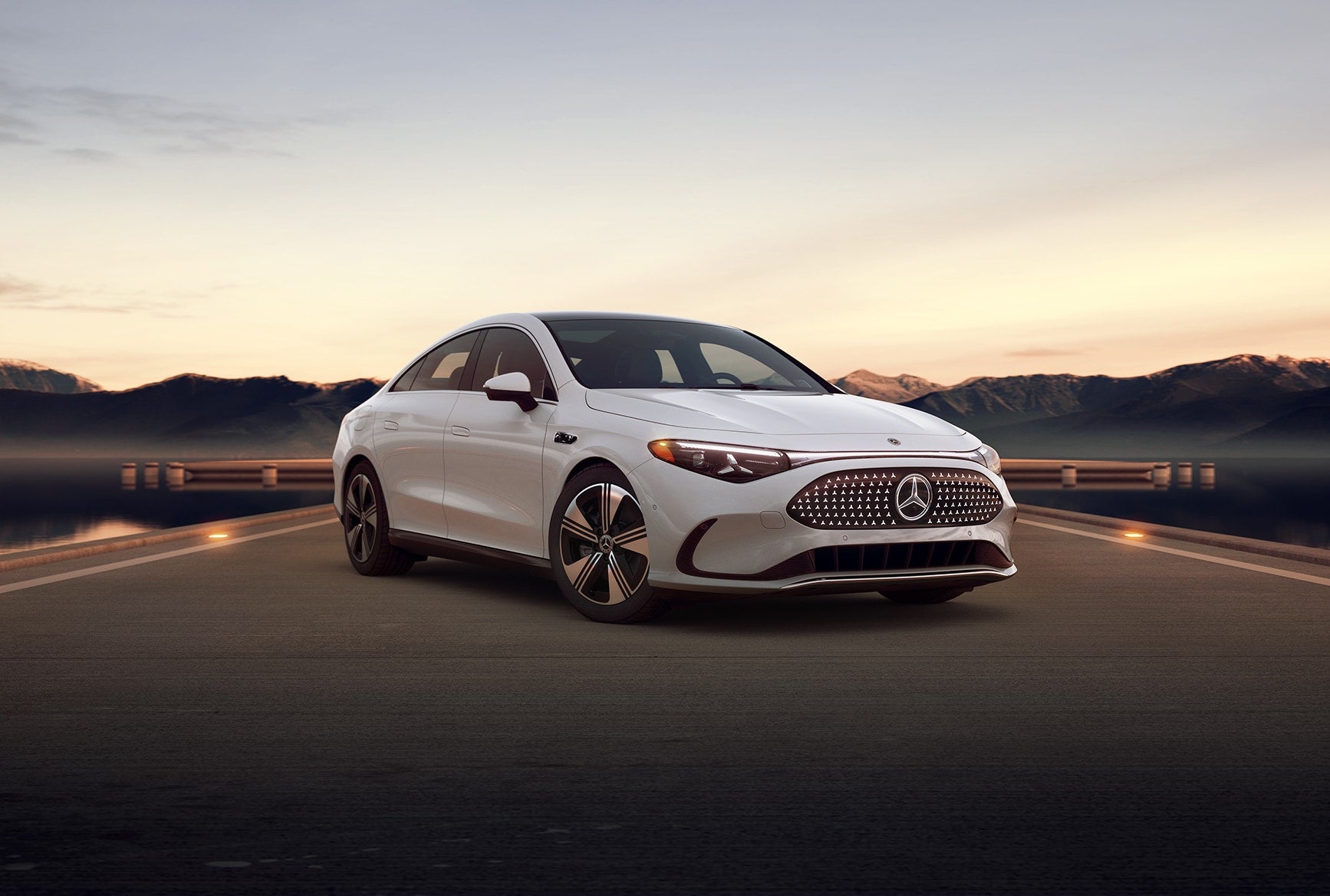 White 2027 Mercedes-Benz CLA Sedan parked on a scenic road at sunset with mountains in the background.