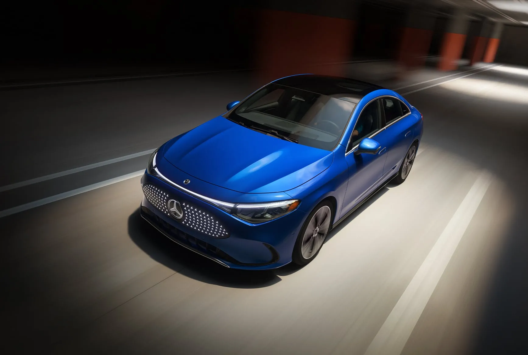 2027 Mercedes-Benz CLA Shooting Brake blue front view driving through a tunnel with illuminated grille.