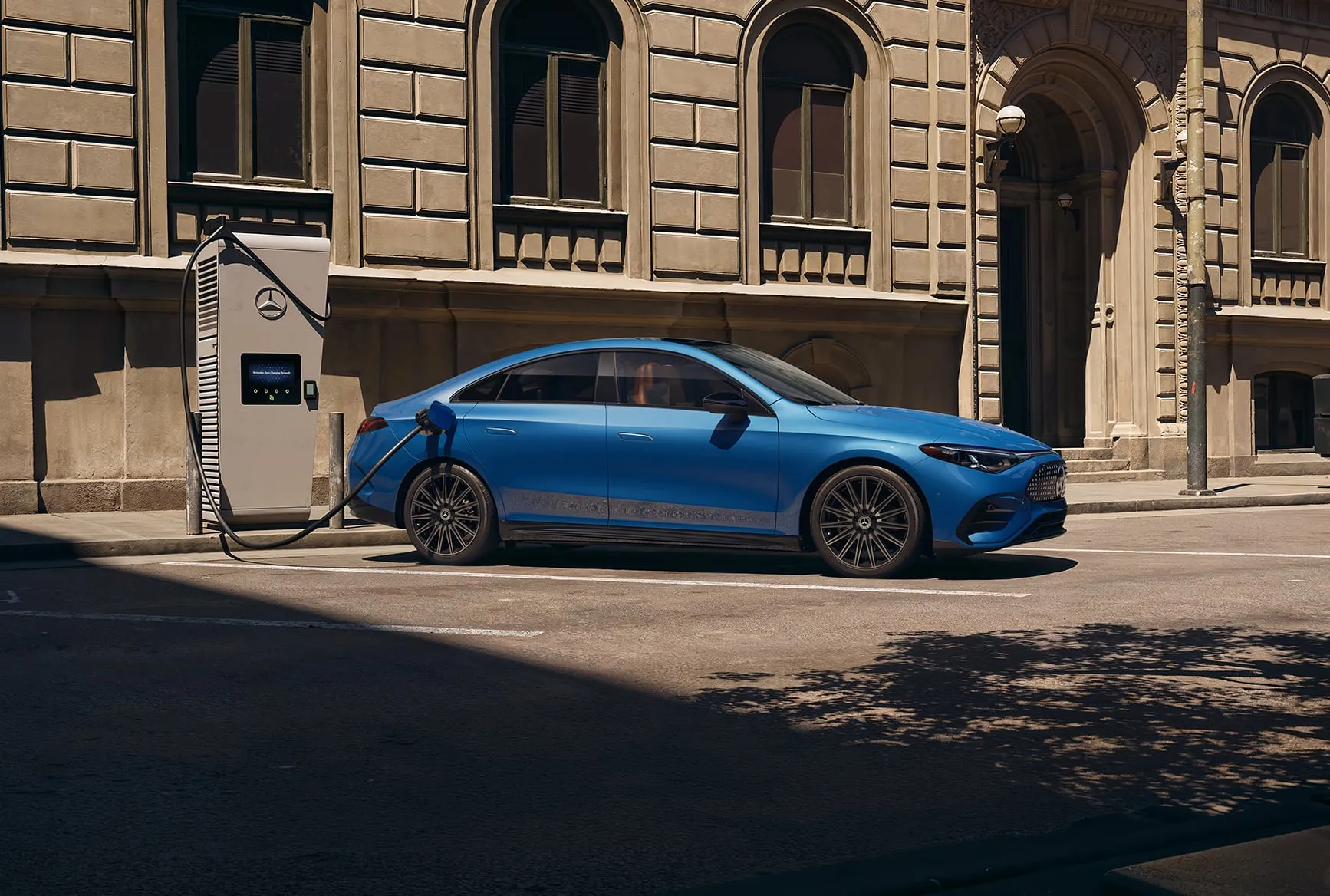 2027 Mercedes-Benz CLA Shooting Brake blue side view plugged into an electric charging station.