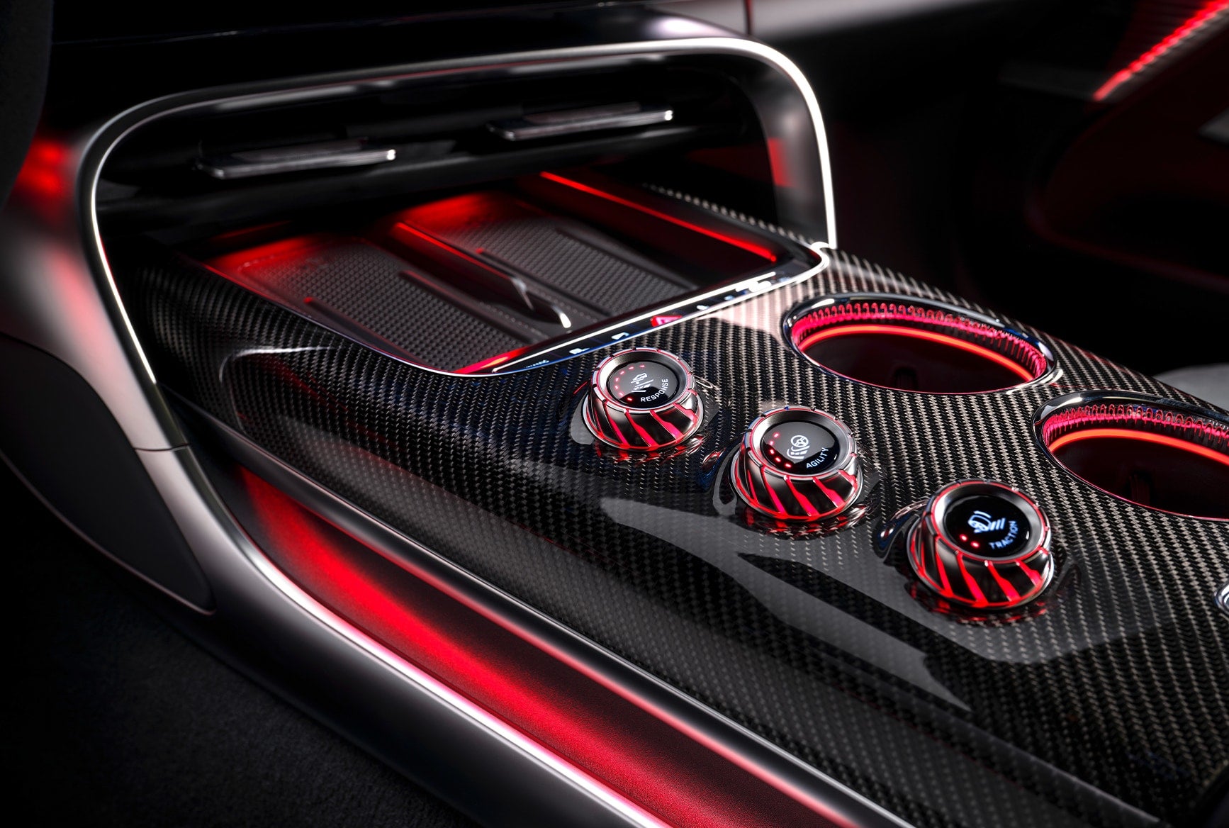 2027 Mercedes-AMG GT 4-Door Coupe interior center console with AMG controls, carbon-fiber trim, cup holders, and red lighting.