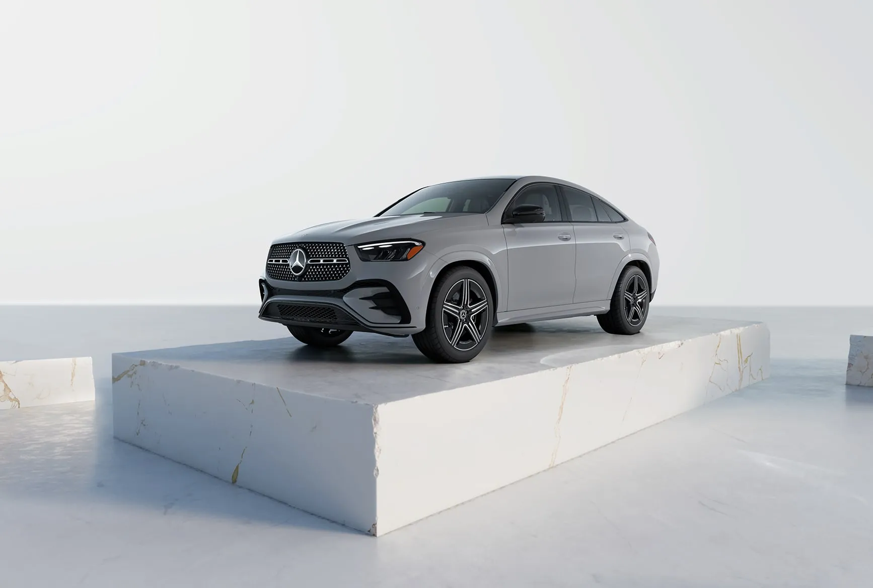 2027 Mercedes-Benz GLE Coupe in silver shown from the front three-quarter angle on a studio platform.