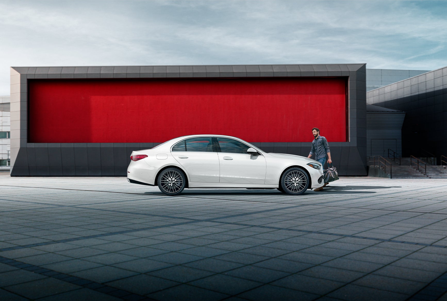 Mercedes-Benz C-Class white luxury sedan parked in front of a modern architectural backdrop