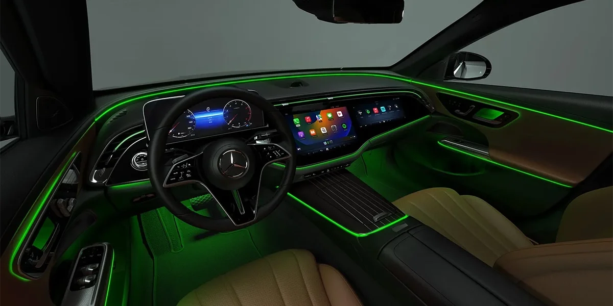 Mercedes-Benz E-Class interior with green ambient lighting, digital display, and modern controls