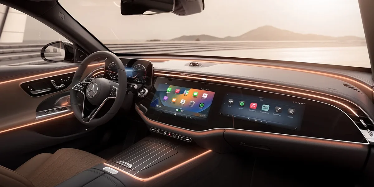 Mercedes-Benz E-Class interior featuring widescreen display, ambient lighting, and modern cockpit