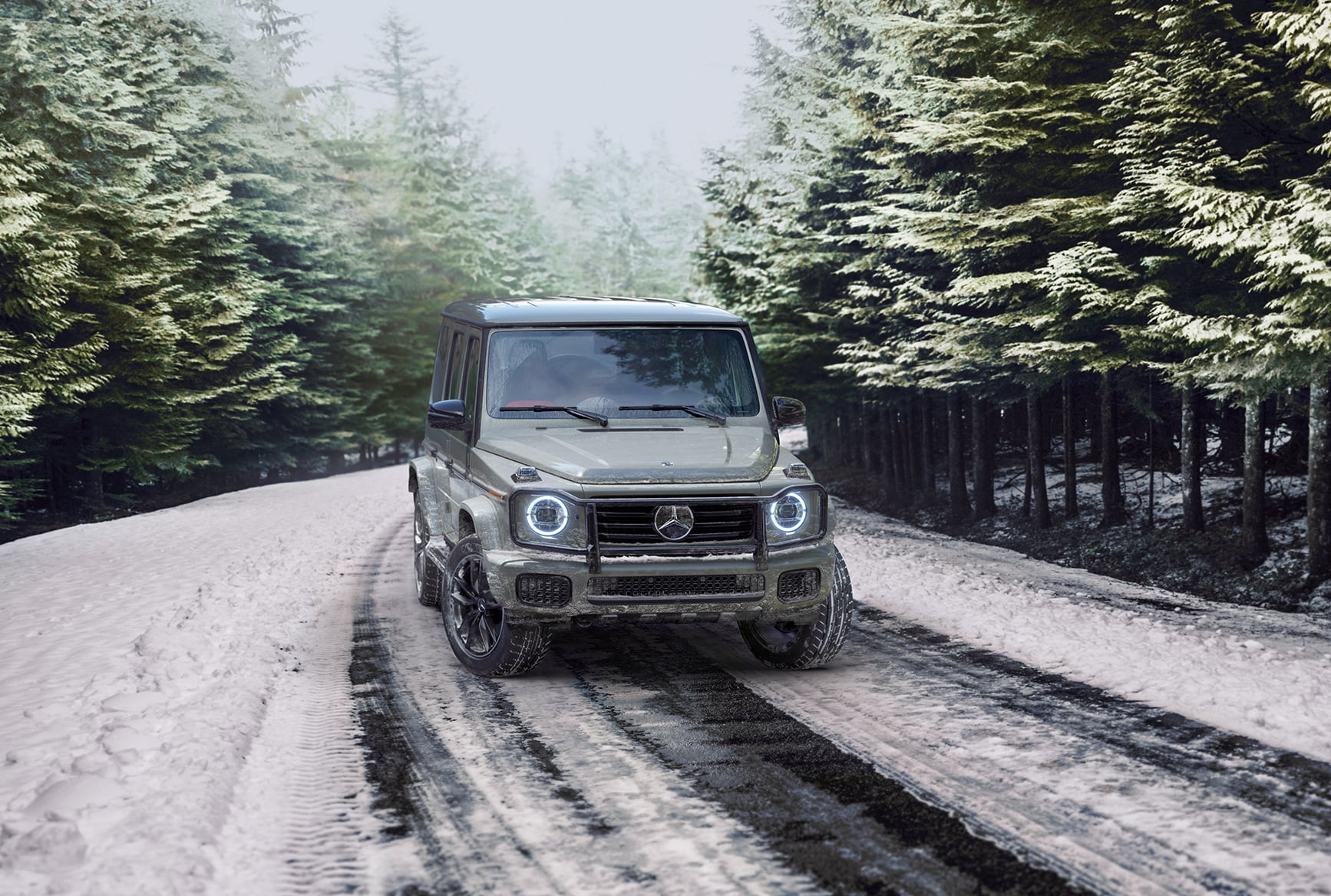 Mercedes-Benz G-Class luxury SUV driving on a snowy road surrounded by pine trees.