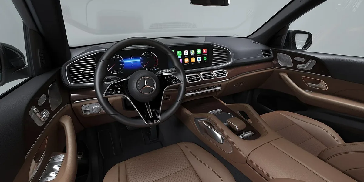 Mercedes-Benz GLS dashboard with digital instrument cluster, central touchscreen, brown leather seats, and wood trim
