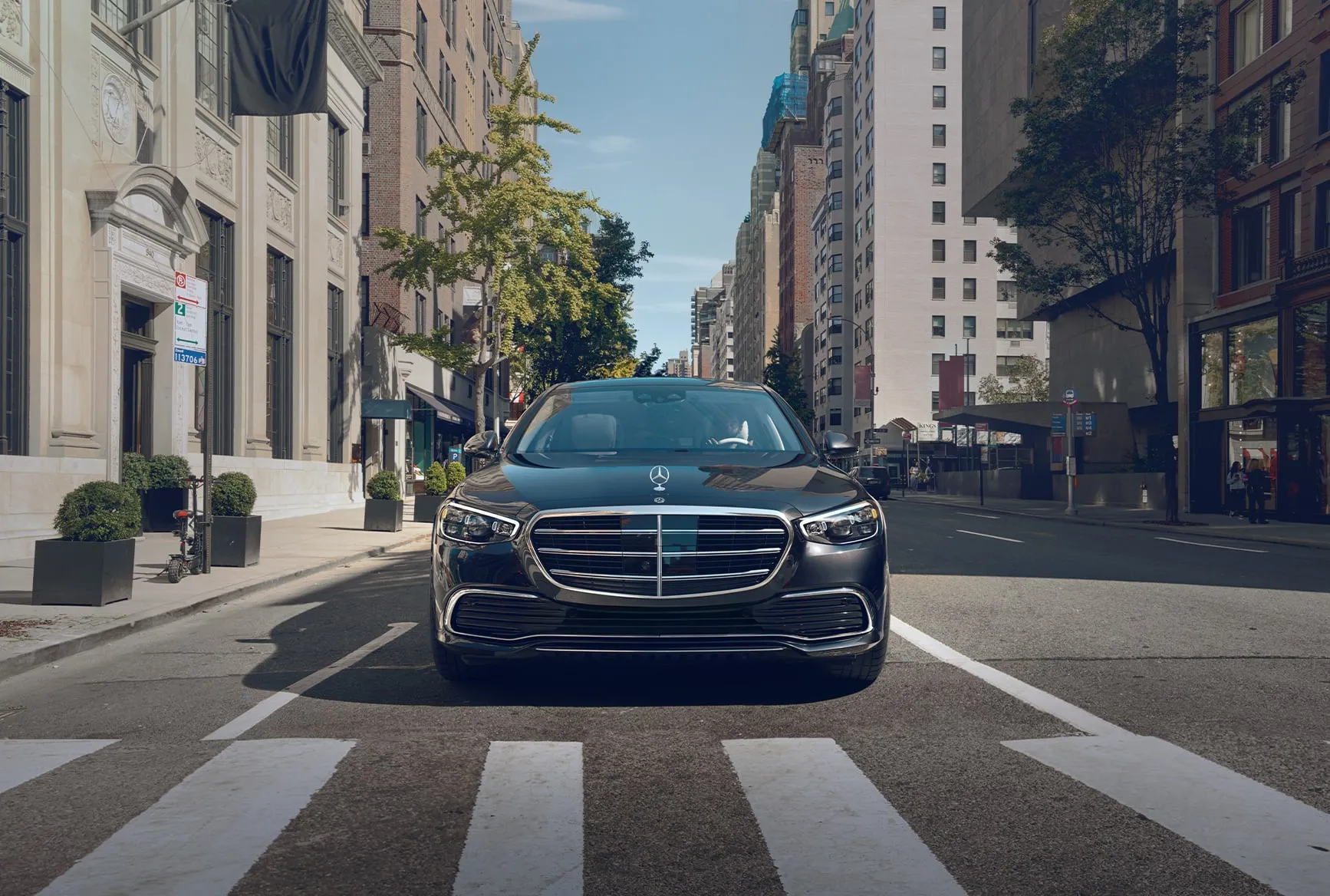 Mercedes-Benz S-Class front grille and headlights in a city street environment
